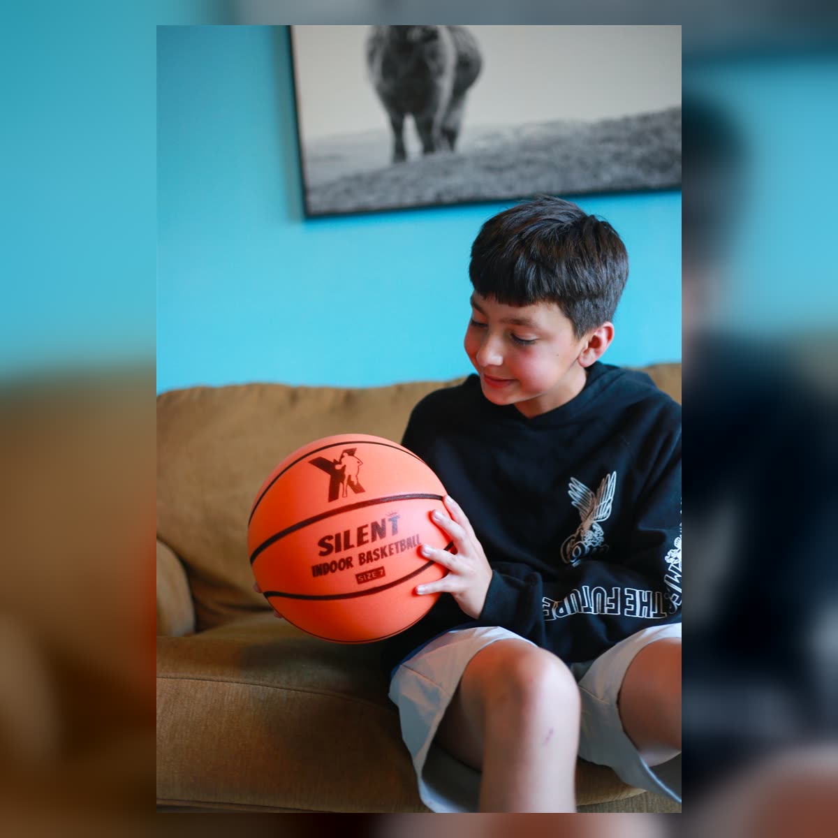 Happy kid holding the YGA Silent Basketball on the couch