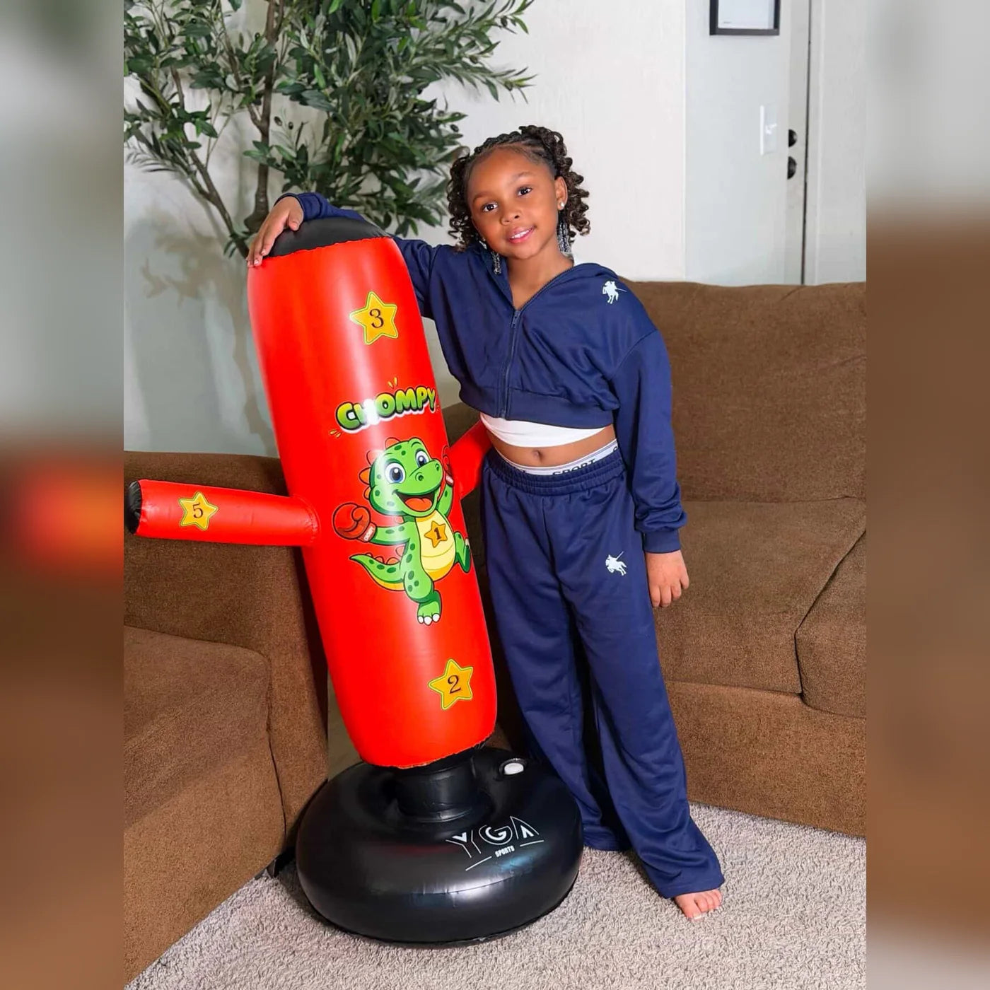 Real customer photo - girl standing proudly with her red Chompy dino inflatable punching bag at home