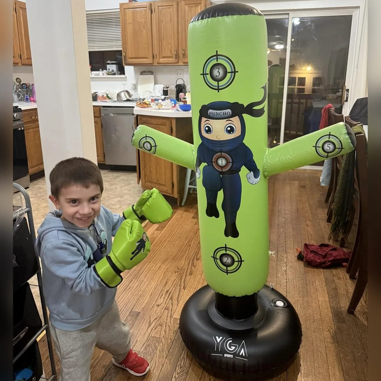 Real customer photo - smiling boy in green boxing gloves next to his green Puncho inflatable punching bag