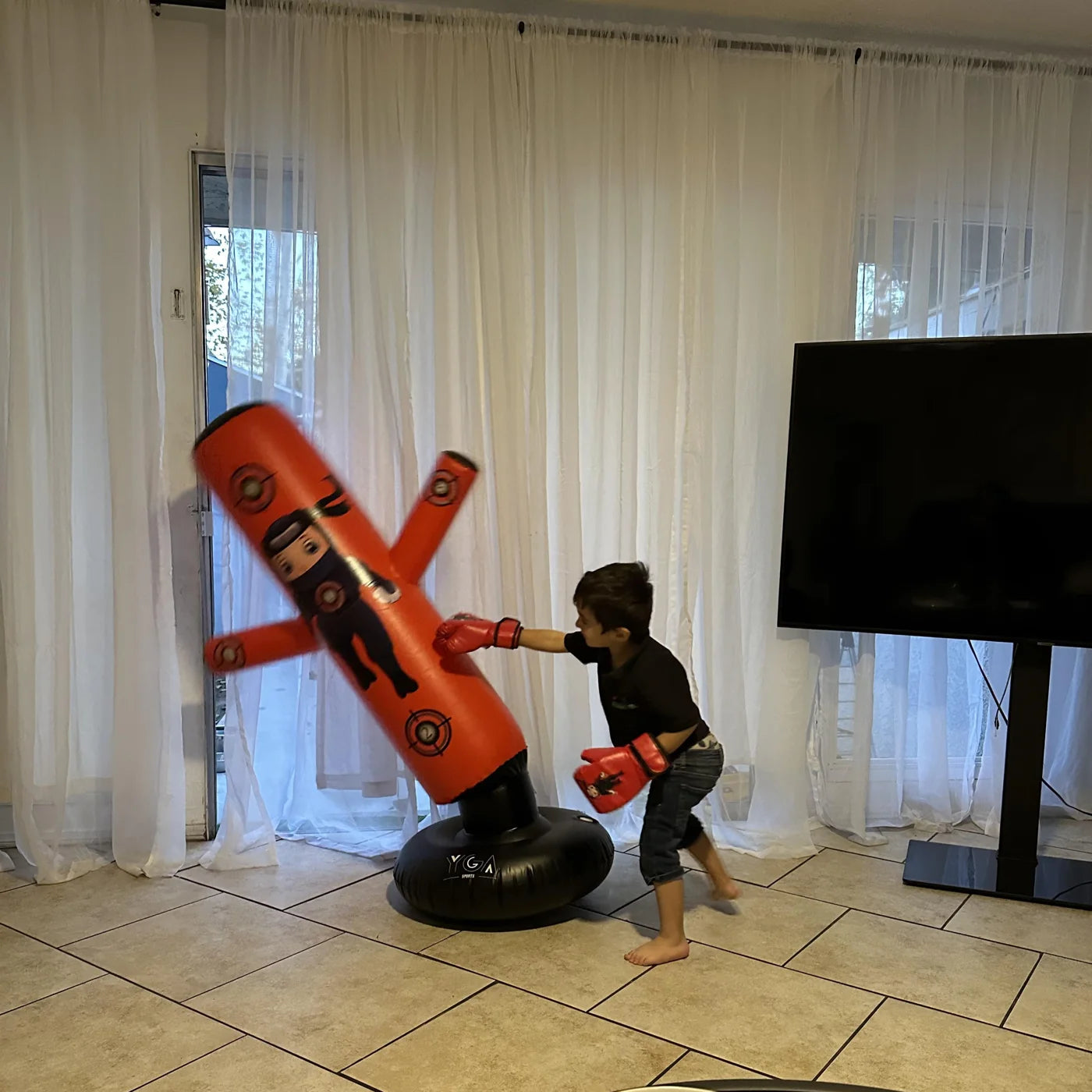 Real action shot - boy landing a punch on the red Puncho punching bag, mid bounce-back